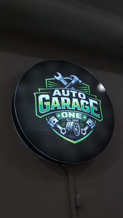 Round illuminated Auto Garage One logo sign on the workshop wall