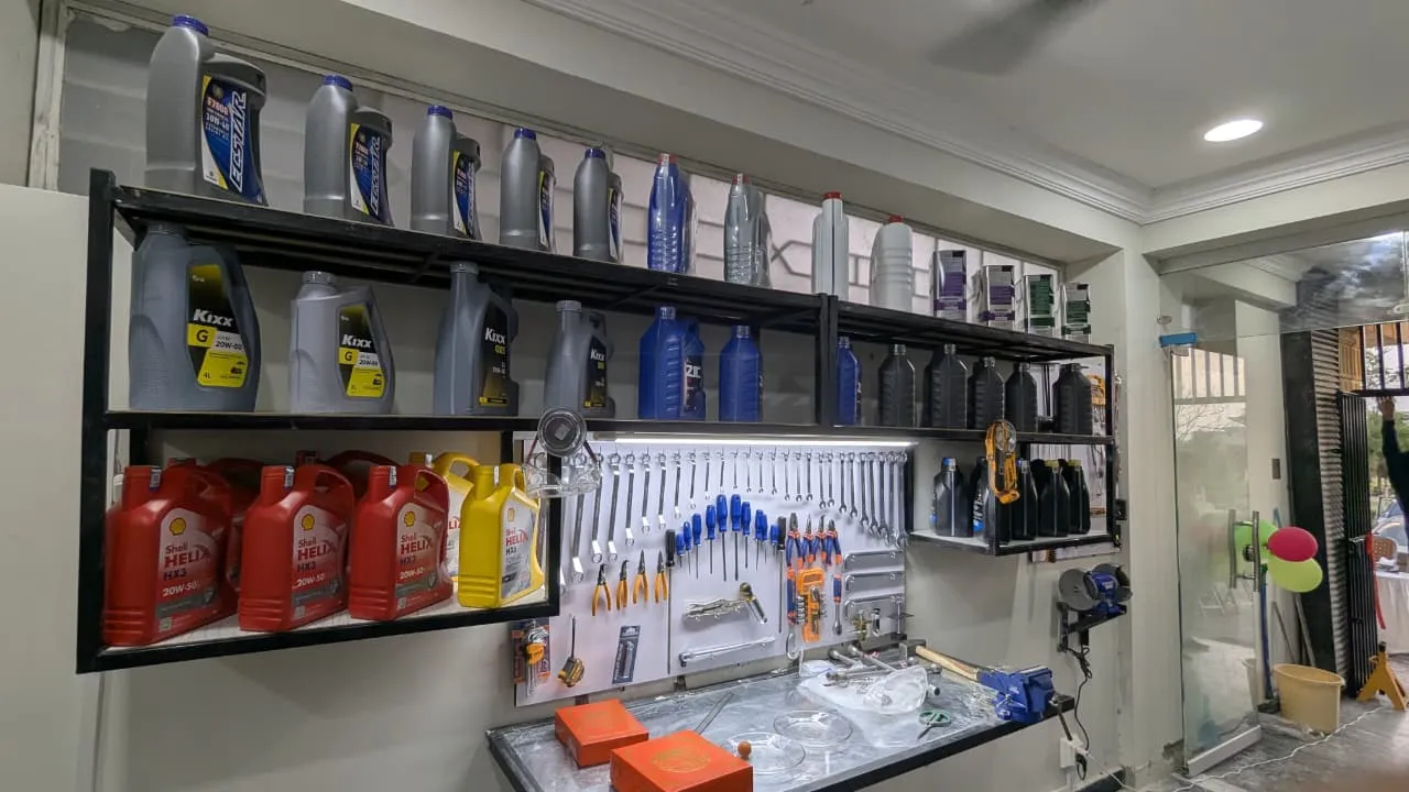 Workbench with a pegboard of hand tools and shelves of engine oils